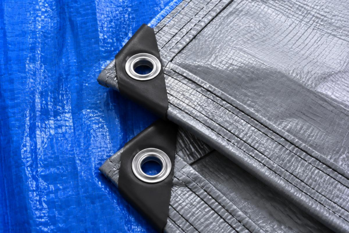 A close up of tarp material showing woven structure and reinforced edges