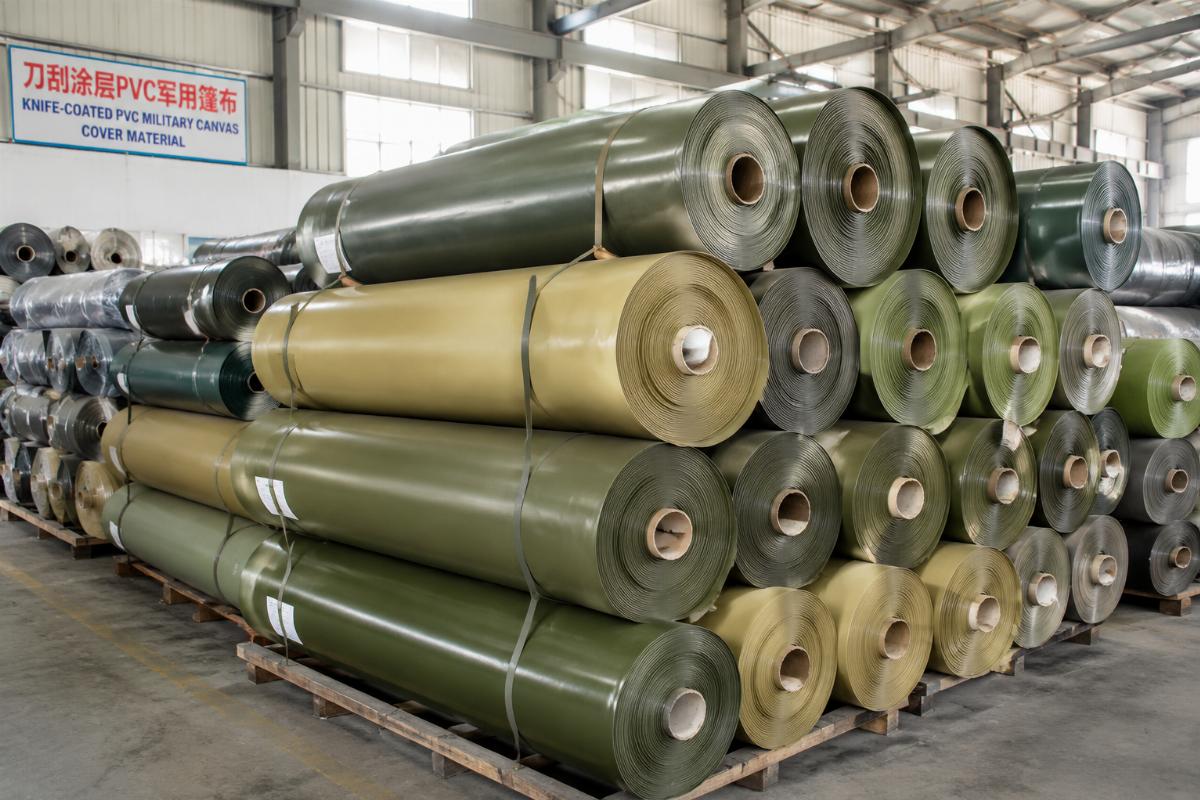Stacked rolls of knife-coated PVC military canvas cover material in a factory warehouse